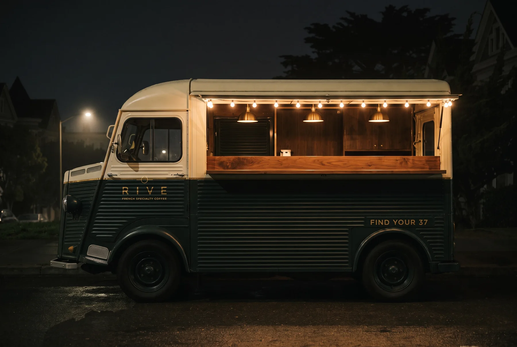 The RIVE 37 truck open after dark, its string of warm bulbs the brightest thing on the street.
